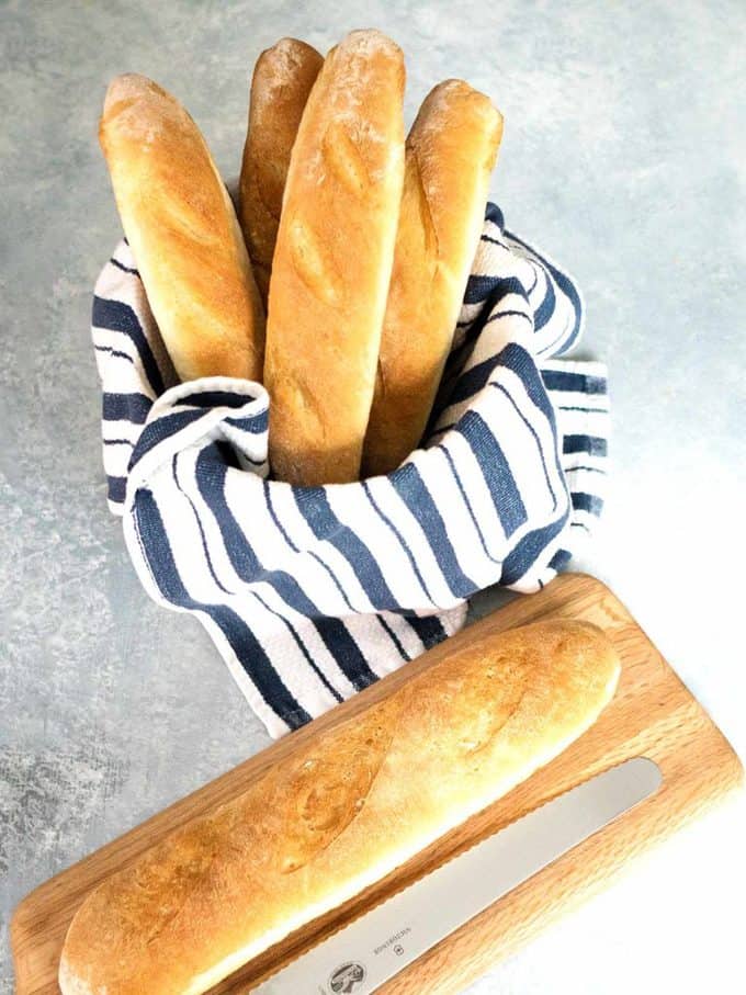 Crusty French Bread wrapped in a blue and white stripped towel.