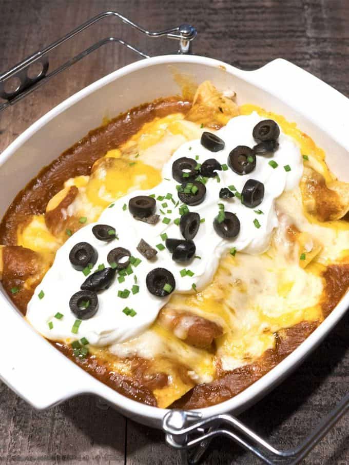 Enchiladas with Awesome Red Sauce in a baking dish topped with sour cream and black olives