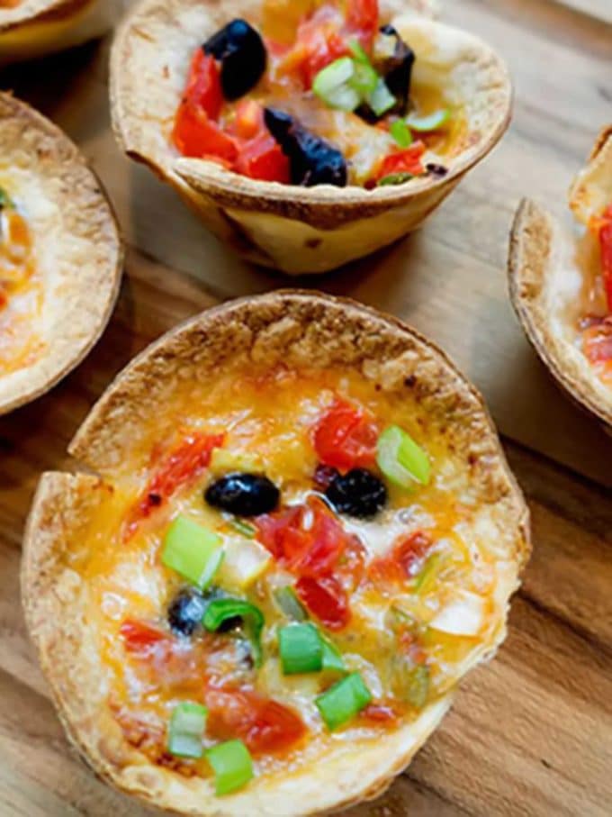 Mini Antojitos topped with melted cheese, olives, scallions, and tomatoes