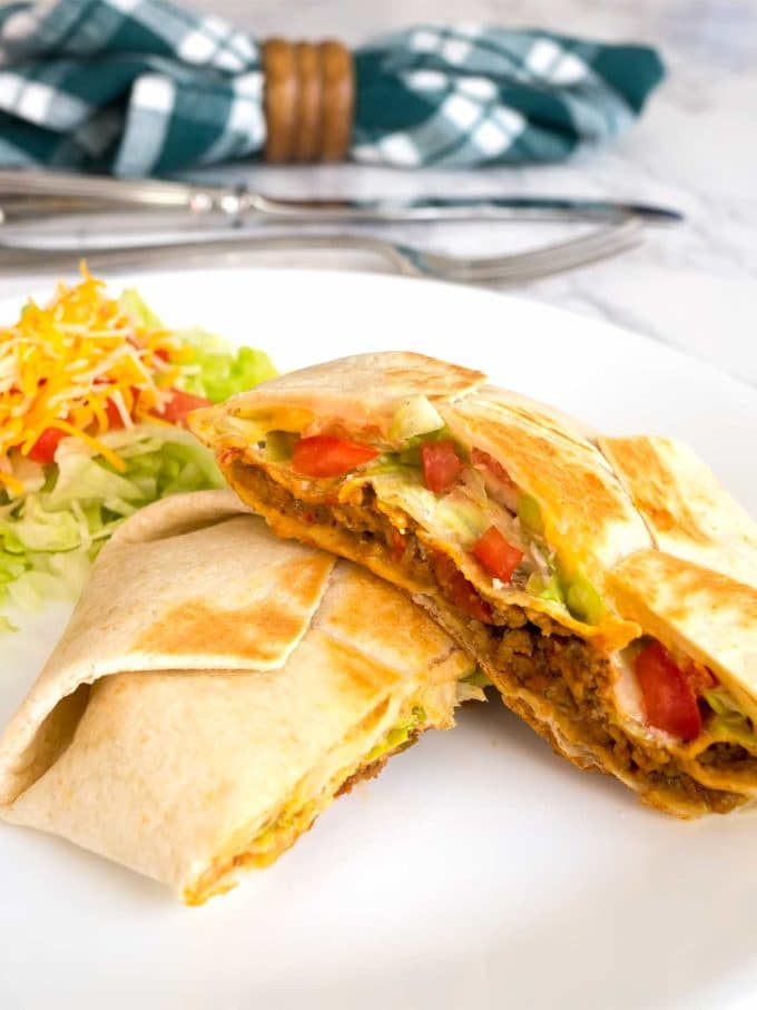 Tasty 7 Layer Quesadilla Wrap cut in half showing the filling with extra cheese, tomatoes and lettuce