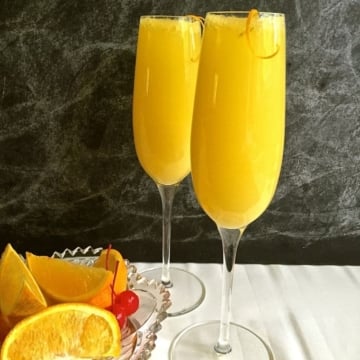 Two champagne flutes full of mimosas.