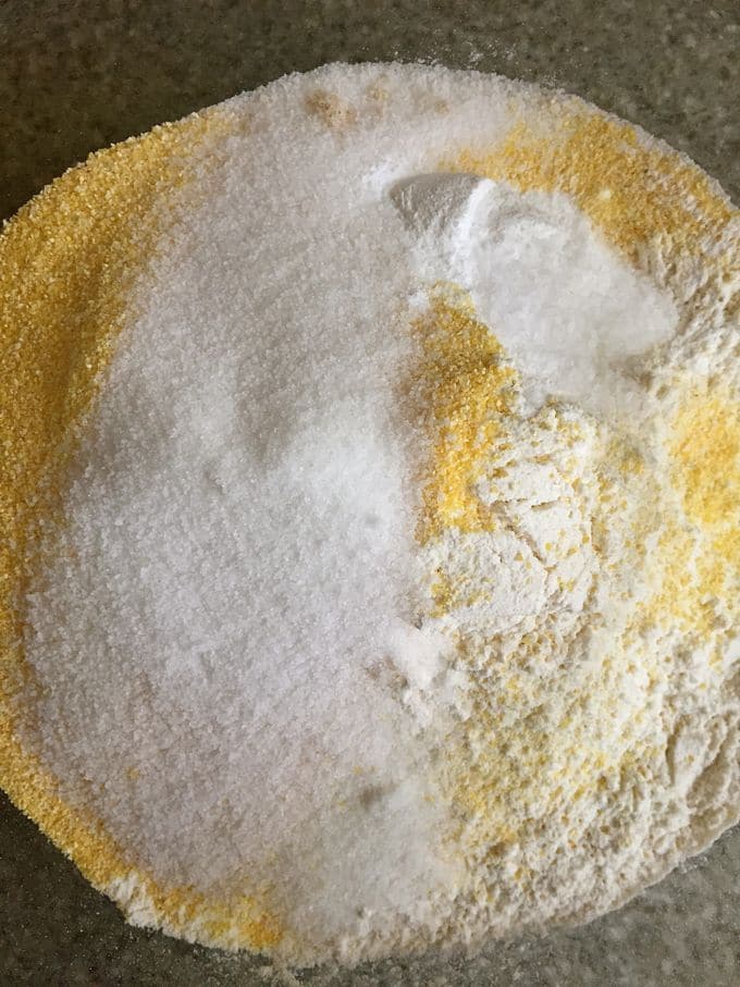 A bowl with cornmeal, flour, sugar and baking powder.
