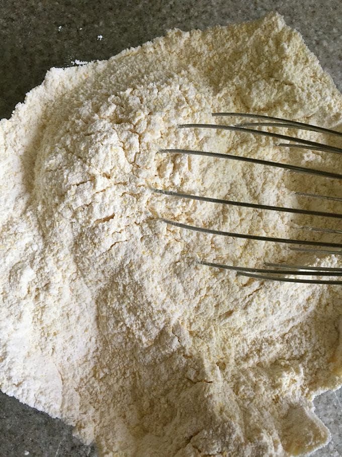 Using a whisk to mix up dry ingredients including cornmeal. 