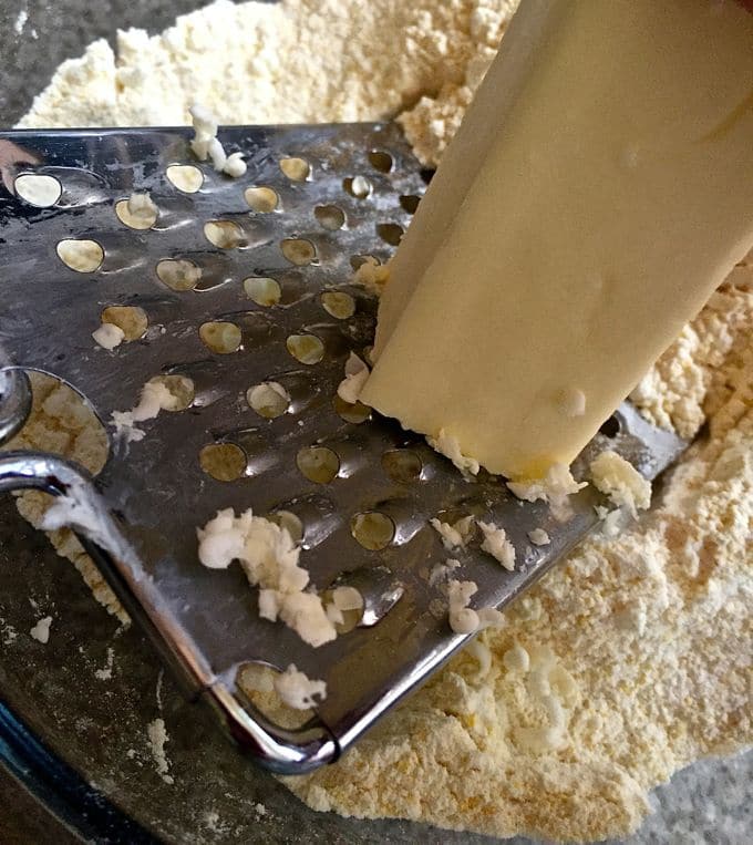 Grating a stick of frozen butter with a grater. 