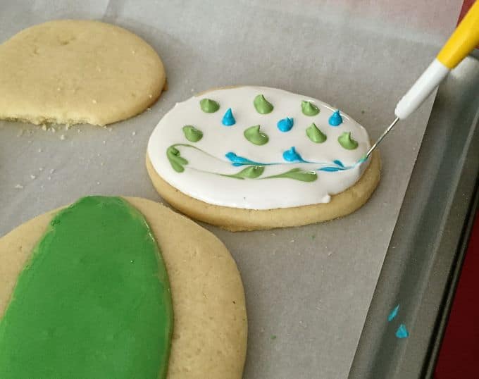 Three sugar cookies on a baking sheet decorated with different colored icing.
