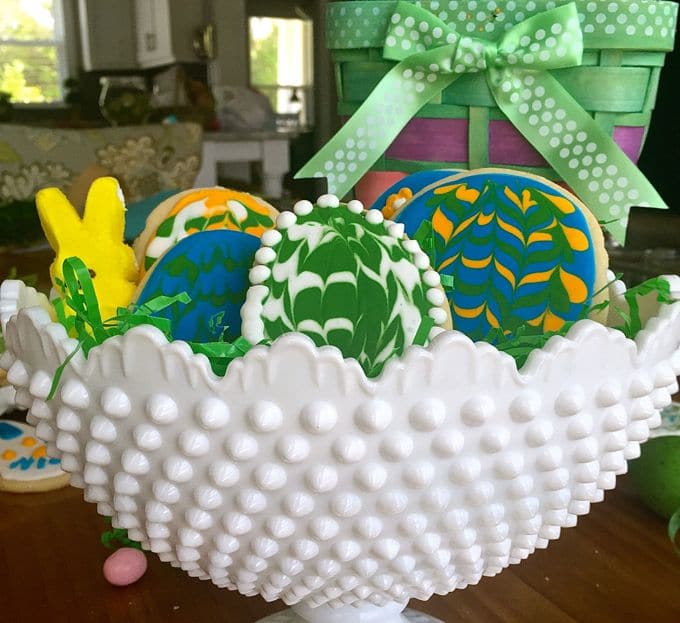 A white bowl full of decorated Easter cookies.