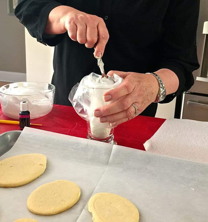 Filling disposable piping bag with icing to decorate sugar cookies.