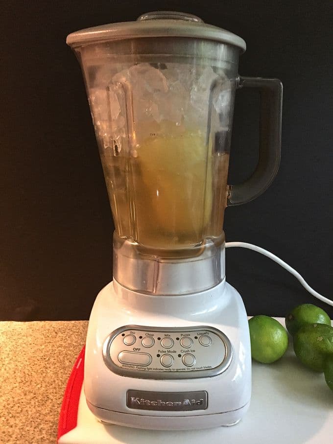 A blender full of ice and the ingredients to make frozen margaritas. 