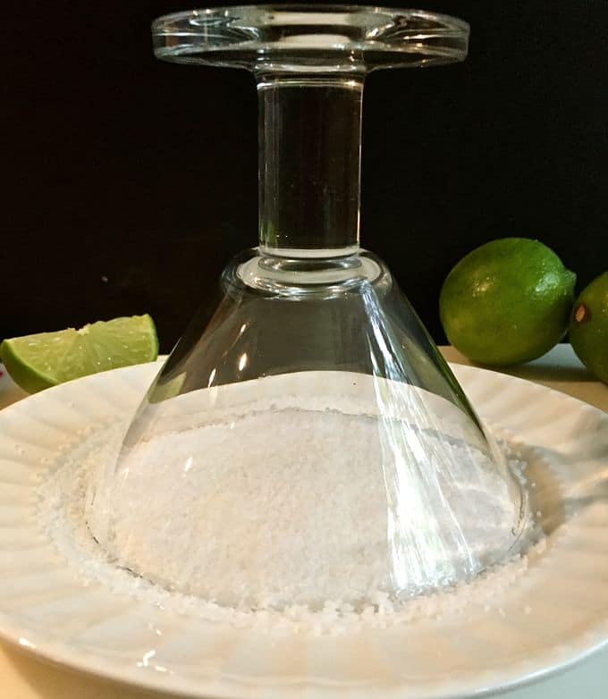 Dipping a margarita glass in a plate full of salt. 