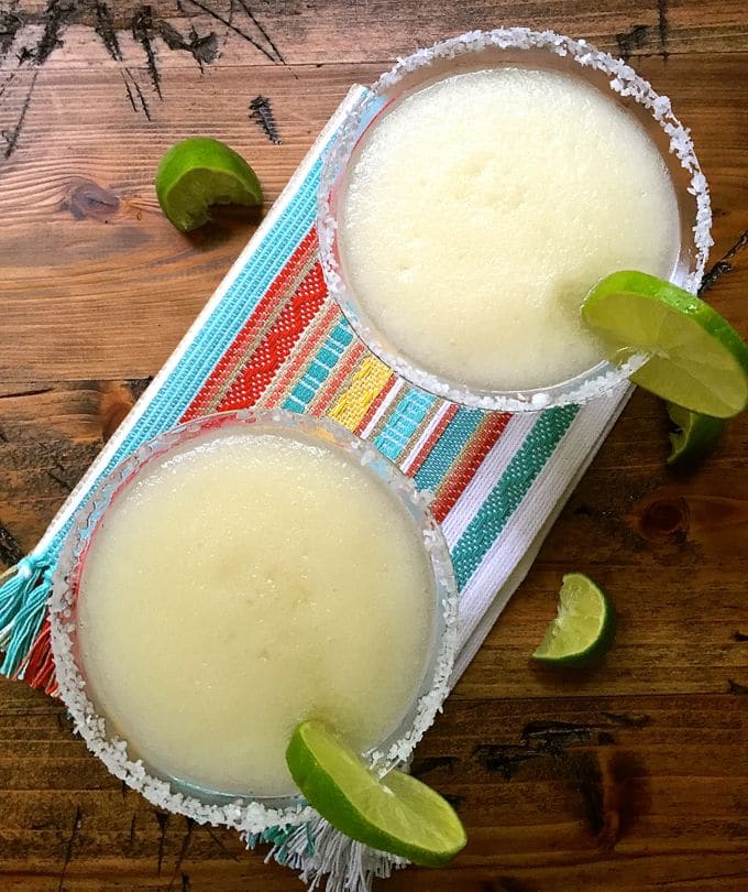 Looking down on two margarita glasses full of the frozen cocktail.