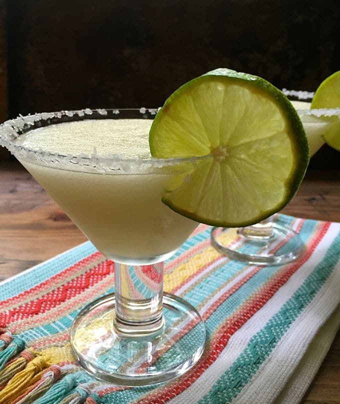 Frozen margaritas in a glass with salt on the rim and garnished with a lime slice