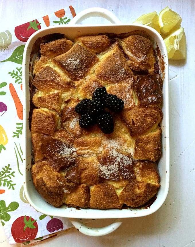 Lemon Blackberry Bread Pudding topped with blackberries in a white baking dish.