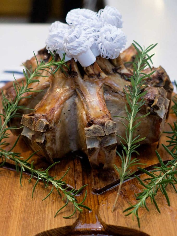 A whole Crown Roast of Pork with Rosemary on a cutting board.