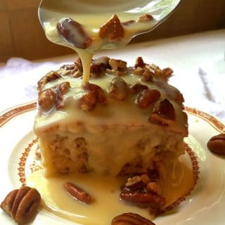 A piece of Southern Pecan Praline Cake with Pecan and Praline topping being drizzled over it