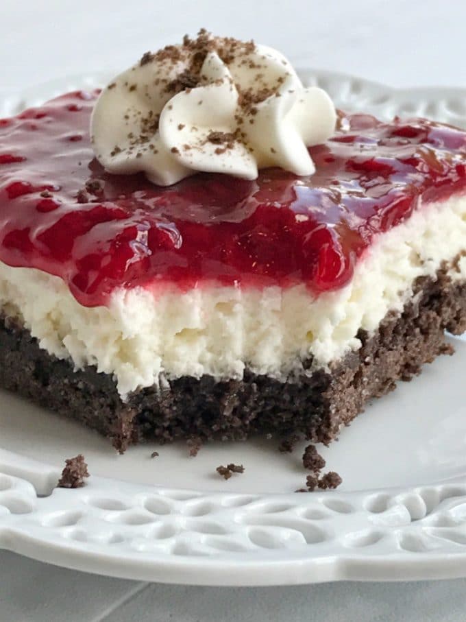 A three layer dessert with a chocolate crust, cheesecake filling and topped with raspberry sauce.