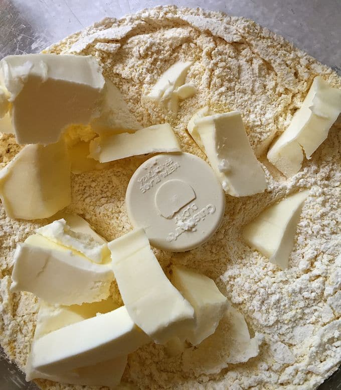 Adding butter to biscuit mix for Tomato Cobbler with Cornbread-Cheddar Biscuits