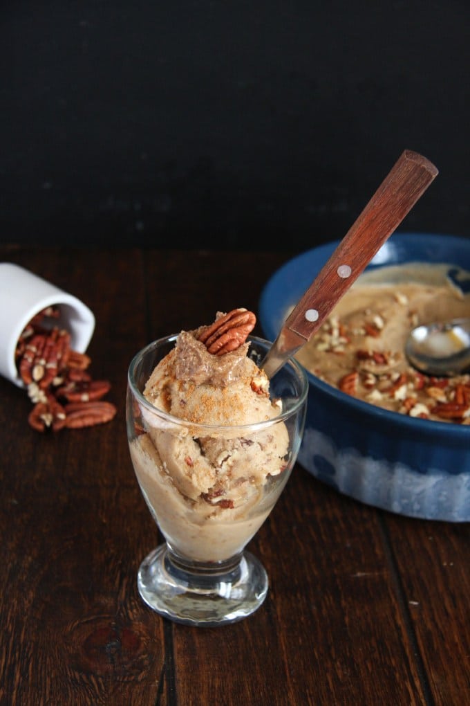 Banana Bread Ice Cream in a clear glass dish topped with pecans. 