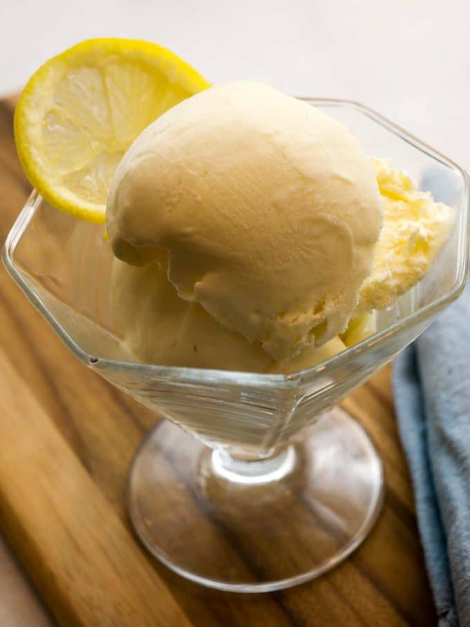 Limoncello Ice Cream in a clear glass dessert dish topped with a lemon slice. 