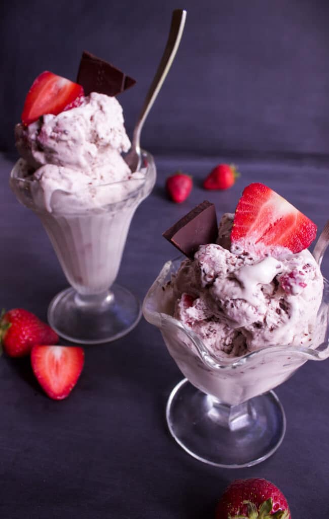 No Churn Red Wine Strawberry and Salted Dark Chocolate Ice Cream in glass dessert dishes topped with sliced strawberries. 