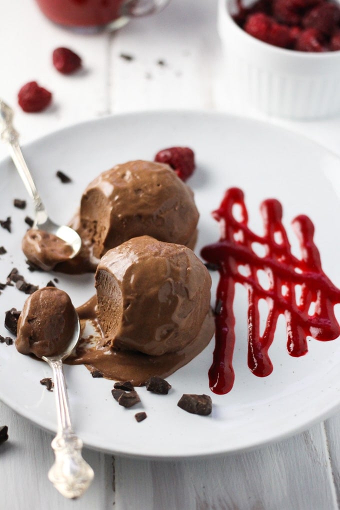 Two scoops of No Churn Vegan Chocolate Ice Cream on a plate garnished with cherry sauce. 