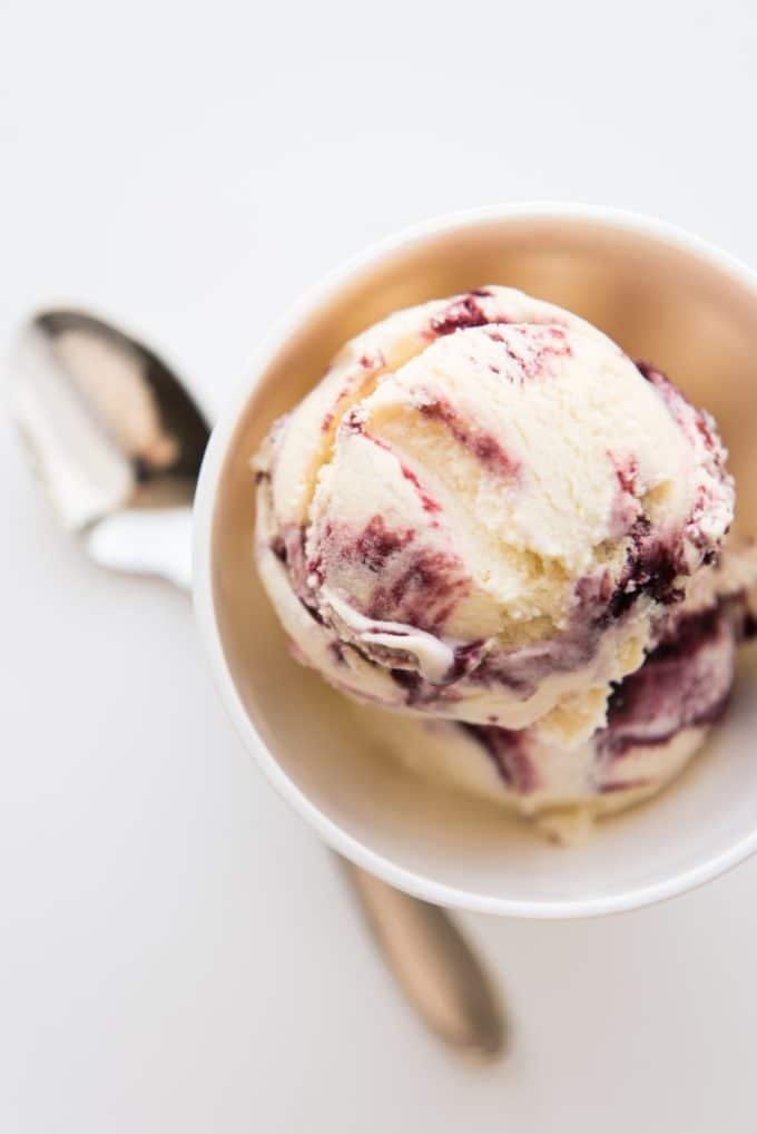 A scoop of Blackberry Swirl Ice Cream in a bowl with a spoon. 