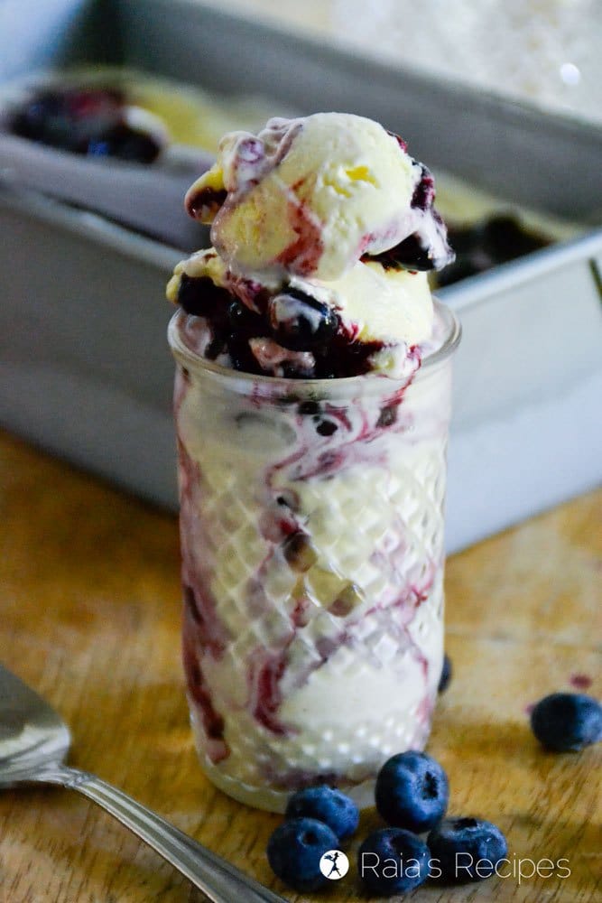 Blueberry Compote Ice Cream in a clear glass jar with blueberries on the table. 