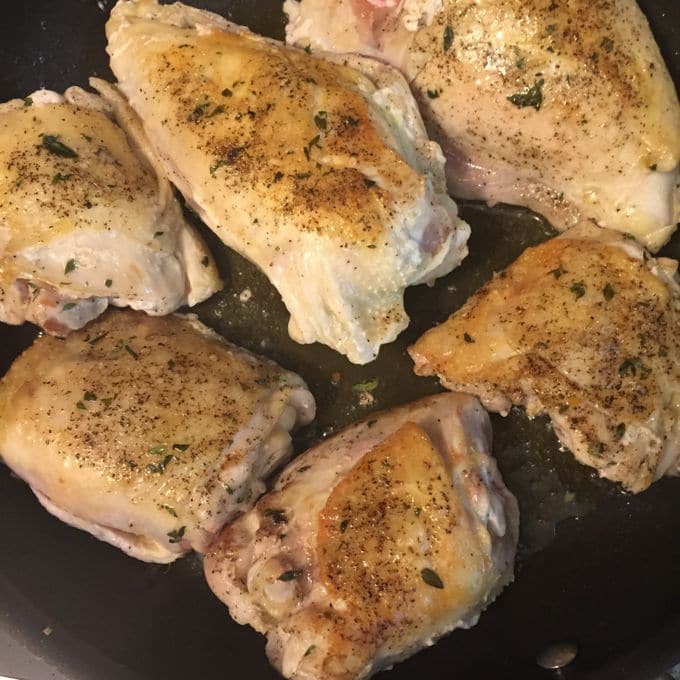 Chicken pieces being sautéed in a cast iron pan for Skillet Chicken with Mushroom Sauce, chicken cooking