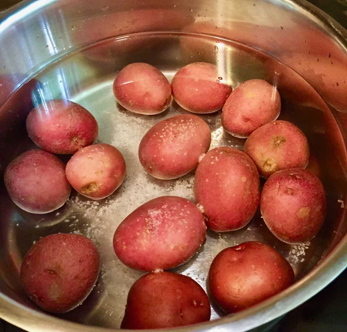 A large pan with potatoes in water on the stove.