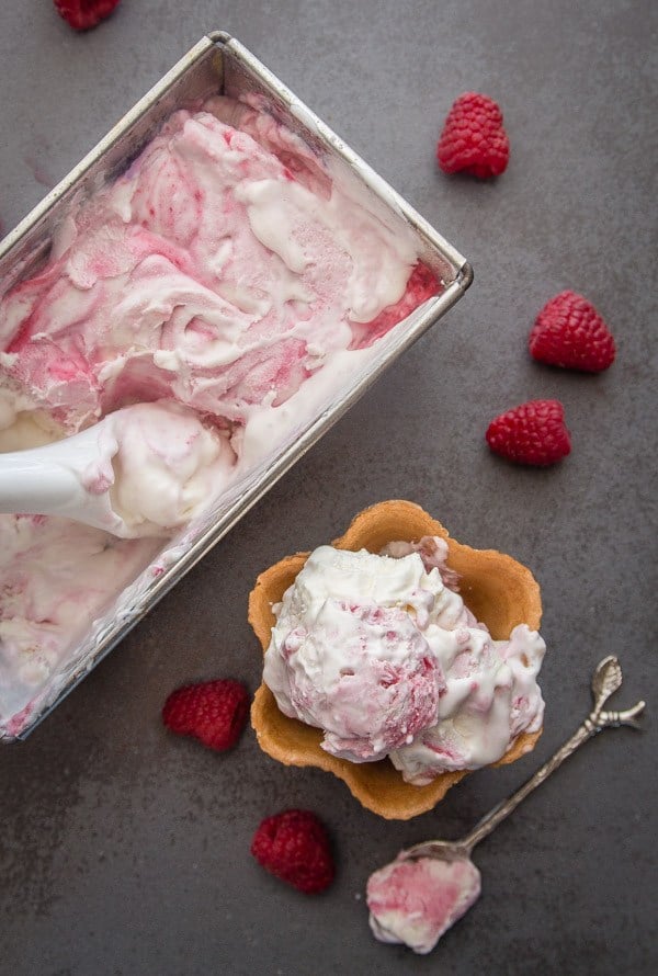No Churn Fresh Raspberry Swirl Ice Cream in a metal loaf pan next to a cone with a scoop. 
