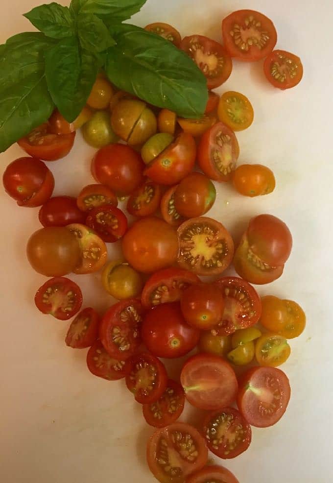 Sliced cherry tomatoes on a cutting board. 