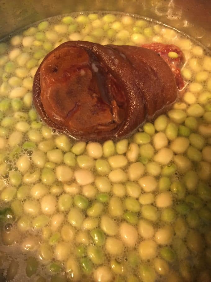 Cooking Southern peas with a ham hock in a saucepan.