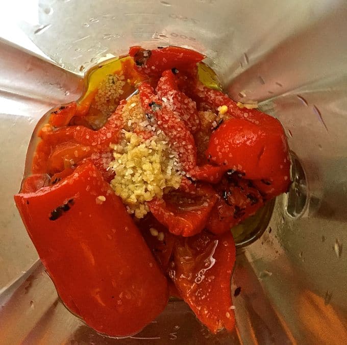 Roasted red peppers and other ingredients in a blender ready to process. 