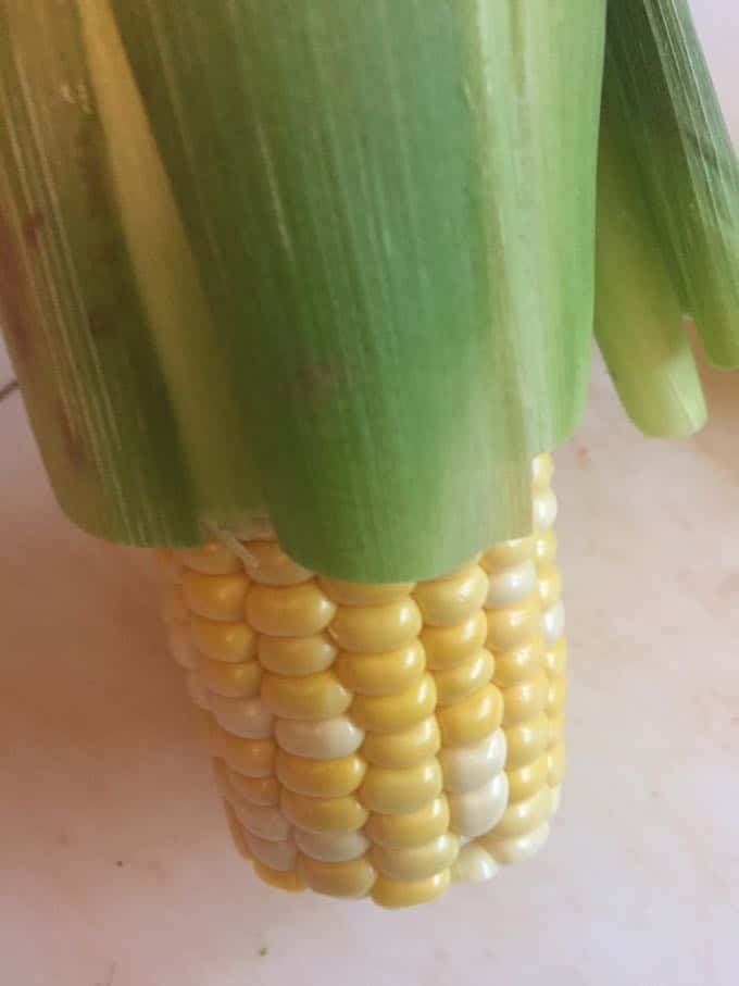 Removing the husk and silk from an ear of corn. 