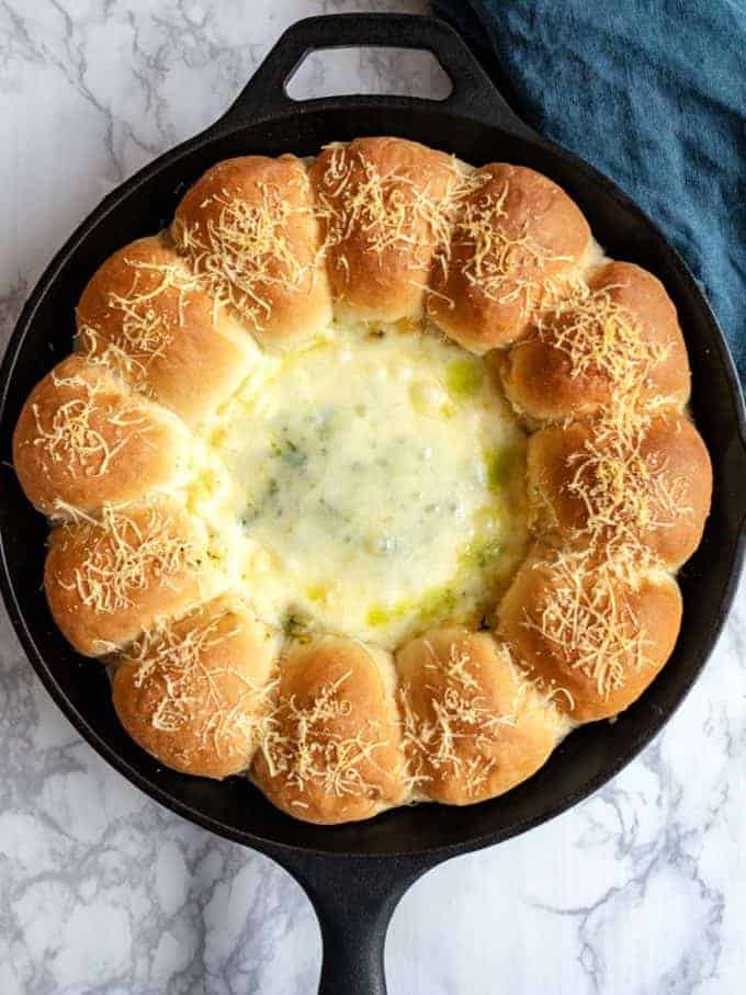 Homemade bread rolls in a cast iron pan with spinach artichoke dip.