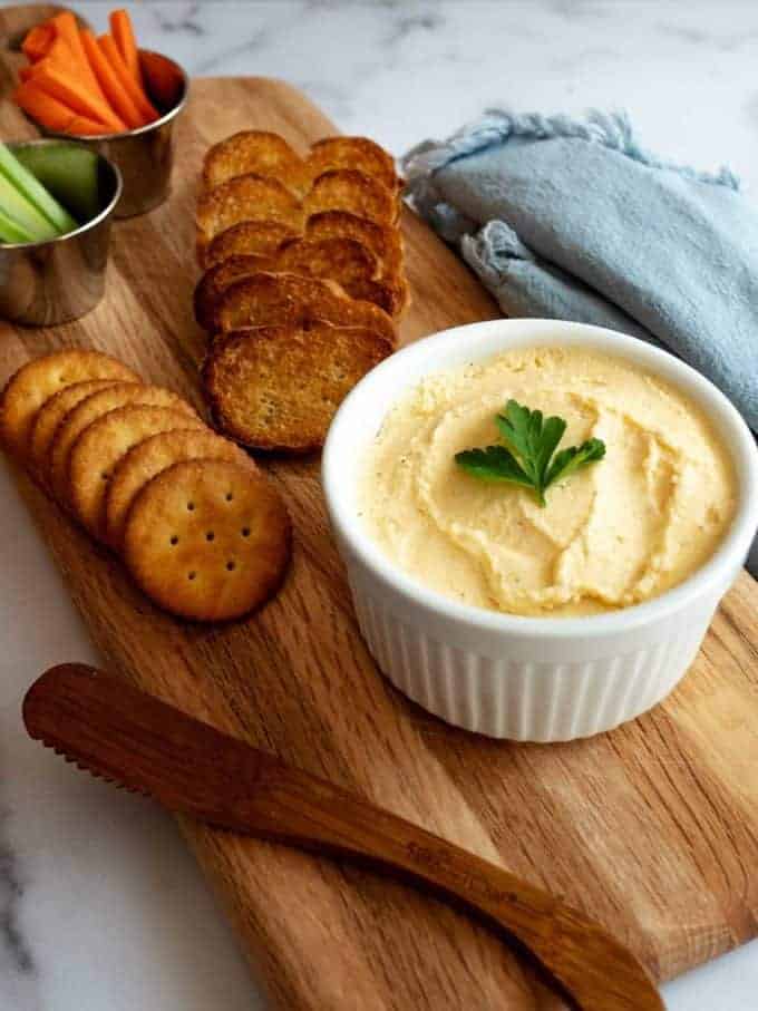 A bowl of fromage fort which is a cheese dip on a wooden cutting board.