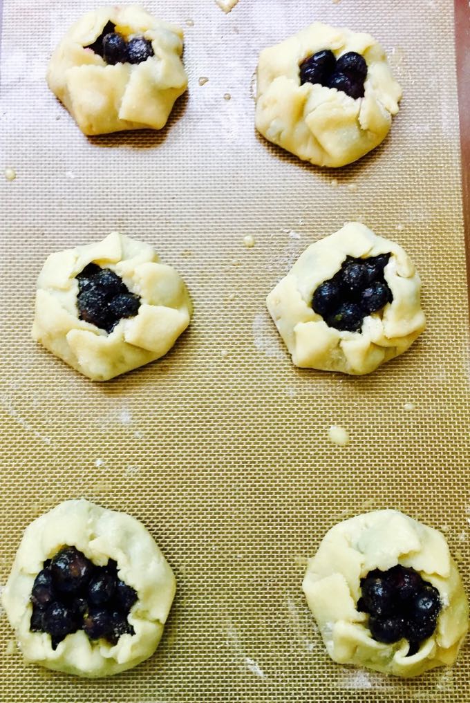 Easy Mini Blueberry Hand Pies ready to bake on a baking sheet ready for the oven.