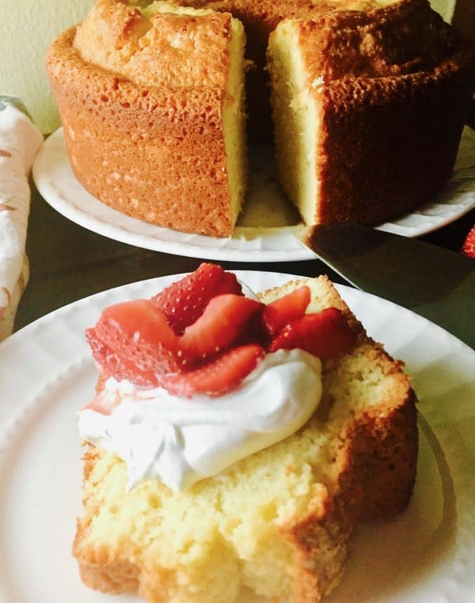A slice of pound cake topped with whipped cream and sliced strawberries. 