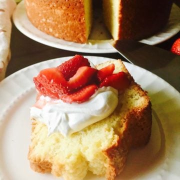 A slice of old-fashioned sour cream pound cake topped with whipped cream and sliced strawberries.