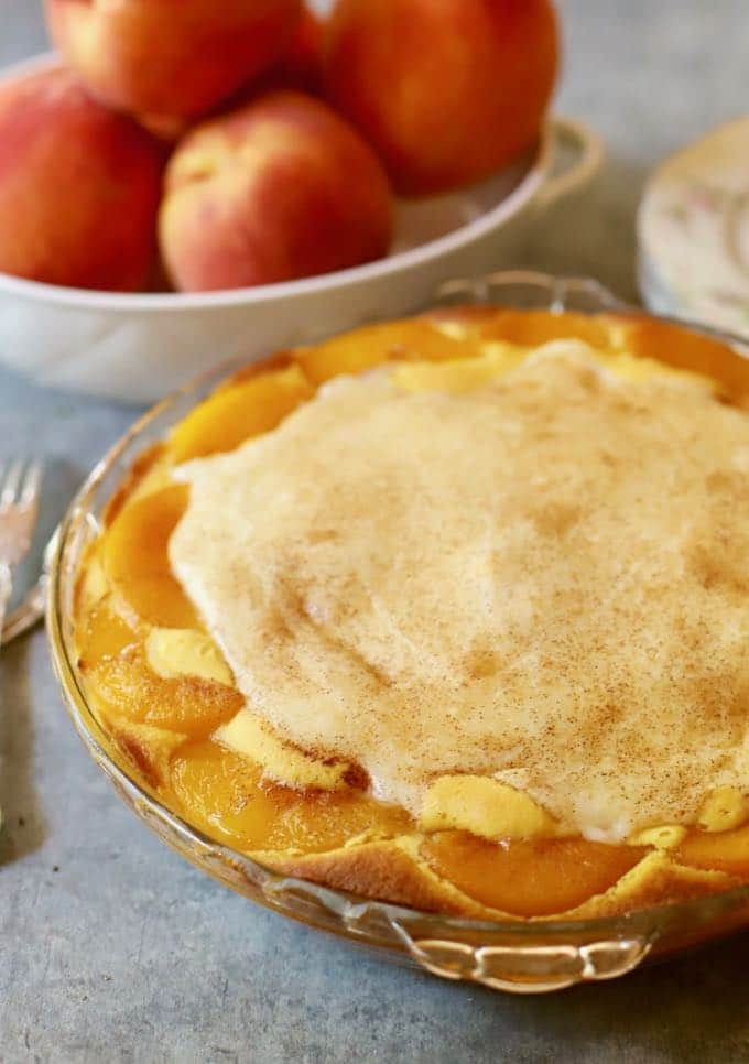 Southern Peaches and Cream Pie next to a large bowl of peaches.