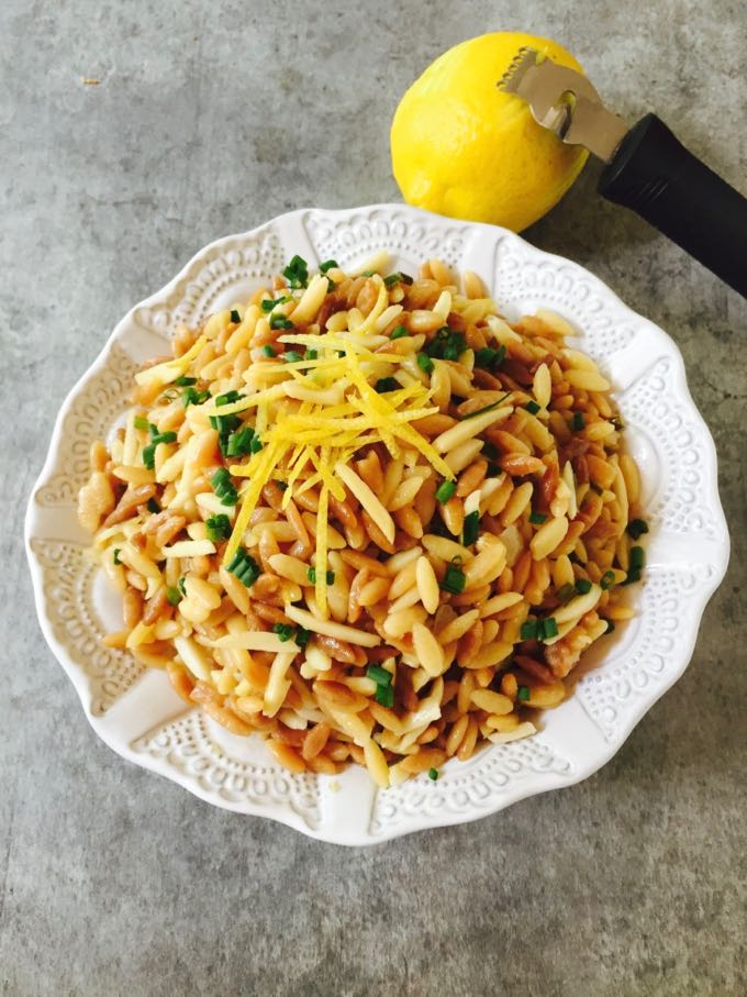 Easy Orzo Pilaf with Lemon and Chives showing lemon being zested