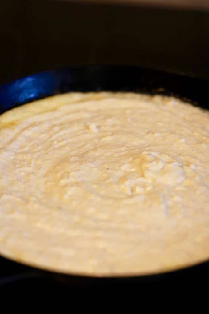 Cornbread batter in a cast-iron skillet ready to put in the oven.