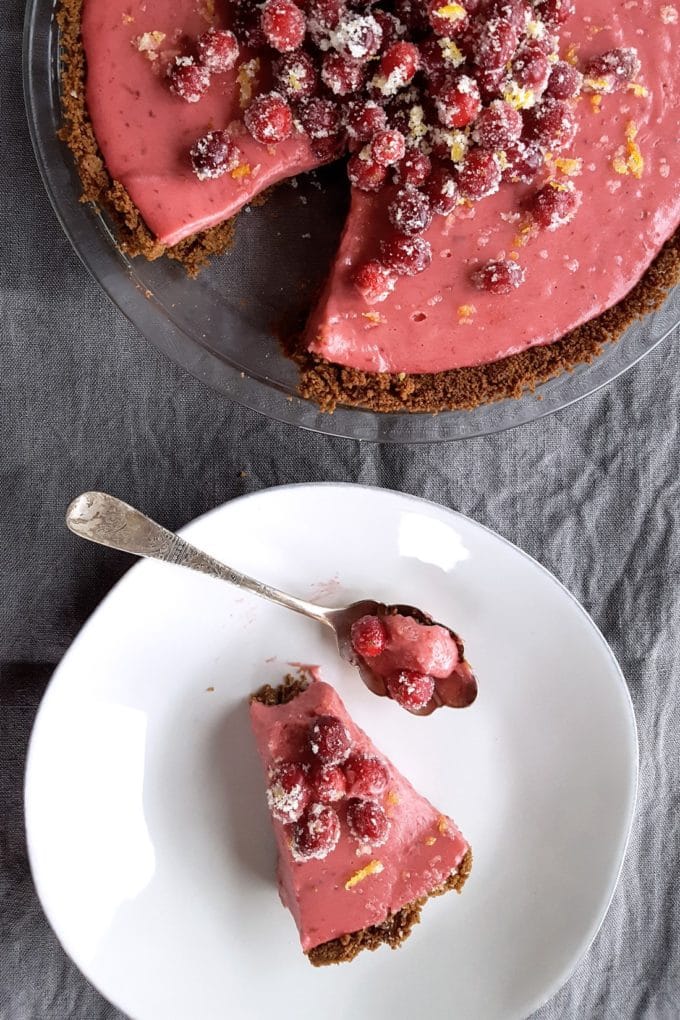 Cranberry Orange Pie in a glass pie plate with a slice cut out. Topped with fresh cranberries and orange zest.