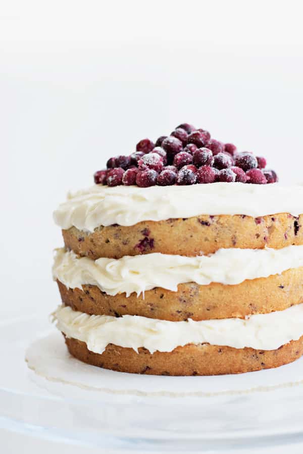 A three layer Cranberry Holiday Cake topped with loads of white icing and fresh sugared cranberries.