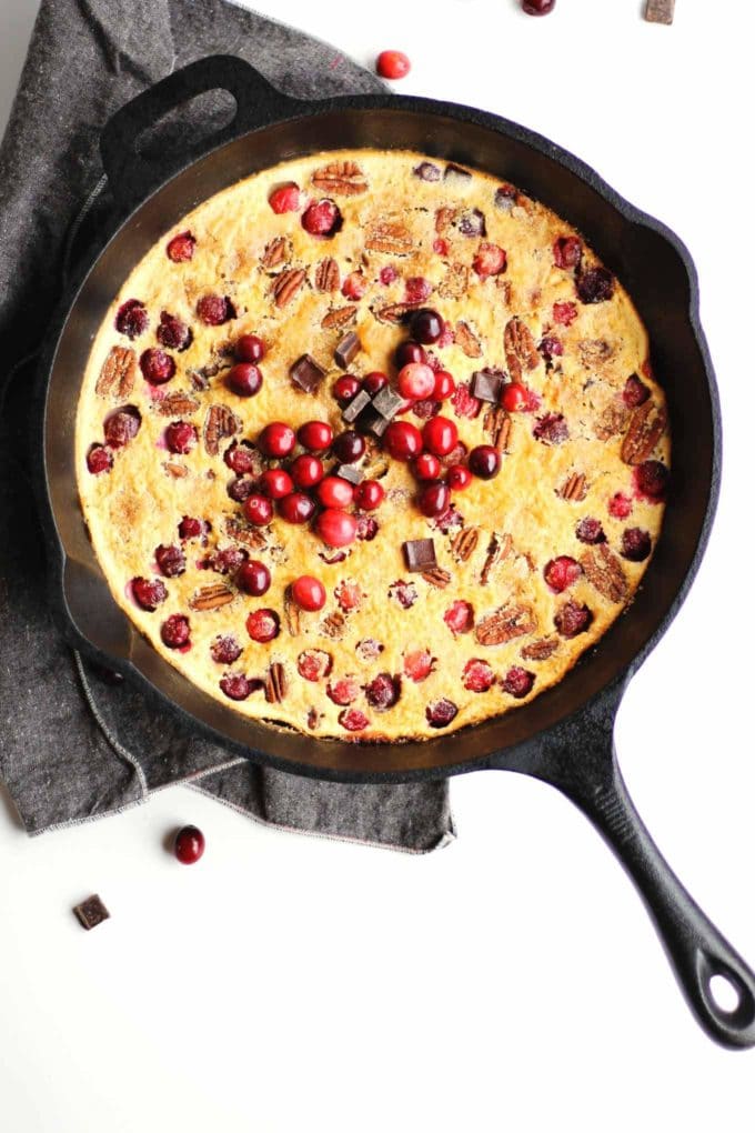 Cranberry Clafoutis in a cast iron skillet topped with fresh cranberries. 