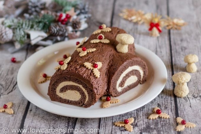 Yule Log Cake on a white platter on a wooden table. 