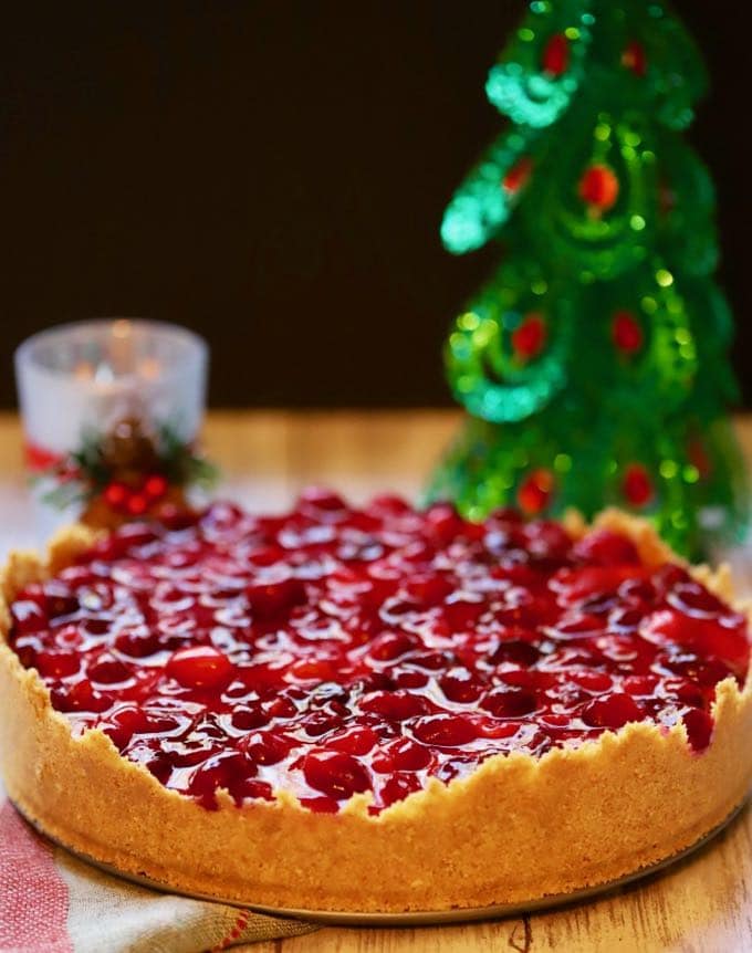Cranberry cheesecake next to a Christmas tree. 