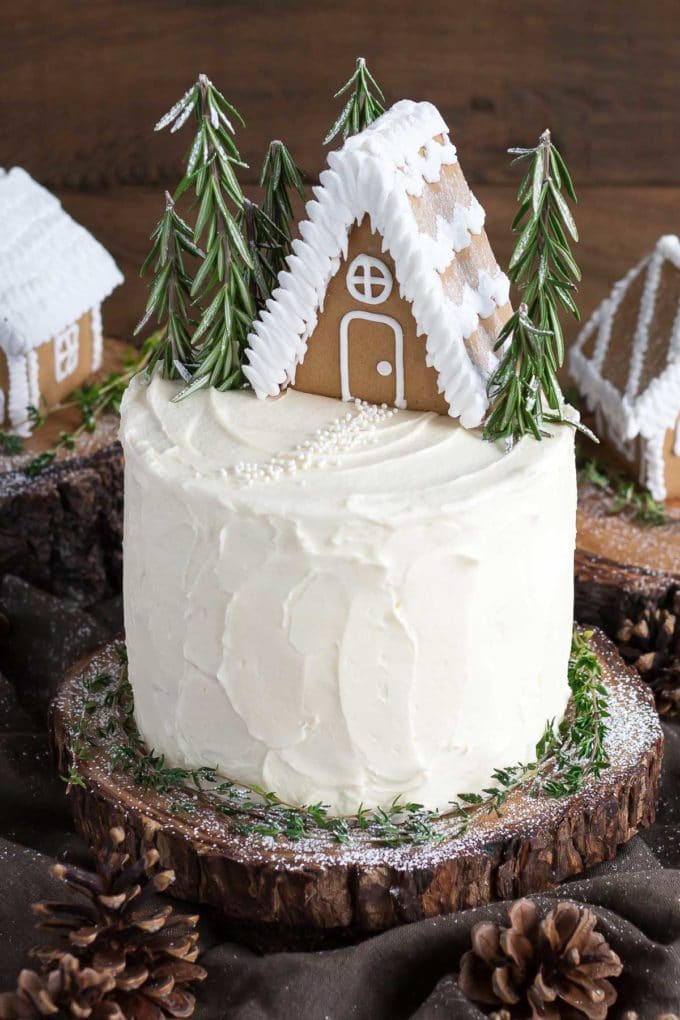 A layered Gingerbread Cake with Cream Cheese Icing topped with a gingerbread house. 