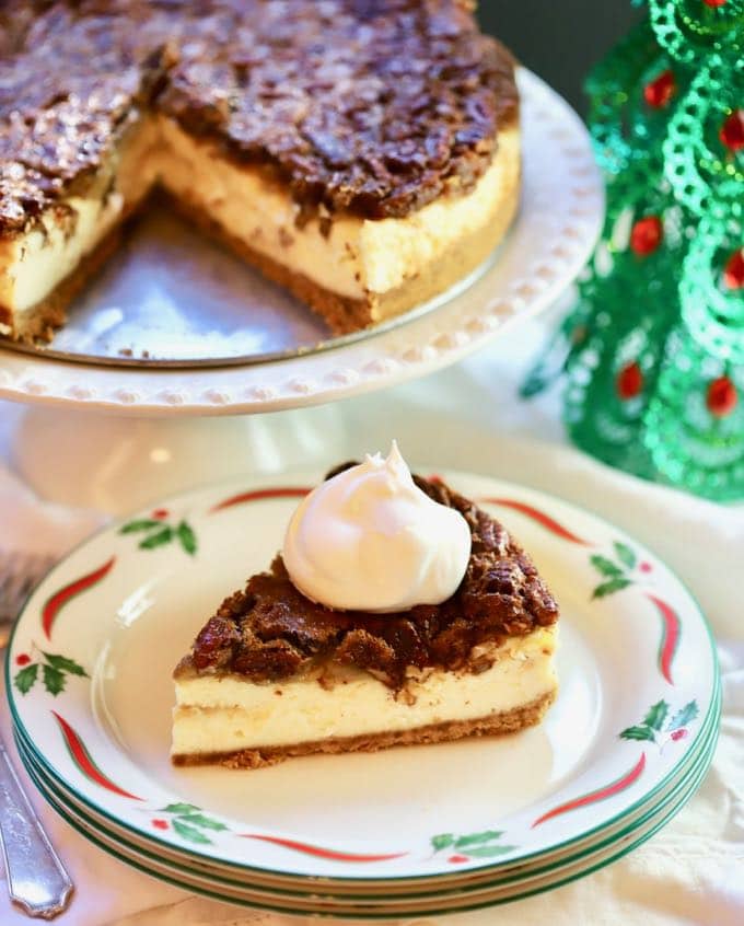 A slice of Southern Pecan Praline Cheesecake ready to serve with a dollop of whipped cream