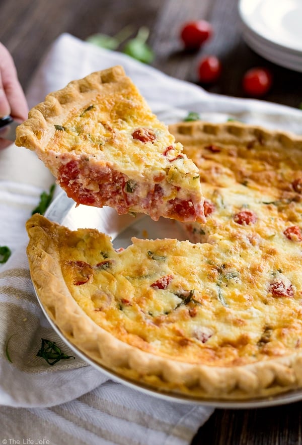 A slice of Caprese Quiche being removed from the while quiche. 