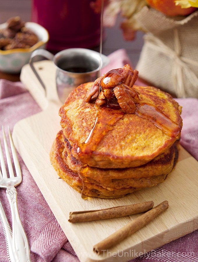 Pumpkin Buttermilk Pancakes topped with pecans with syrup being poured on top. 